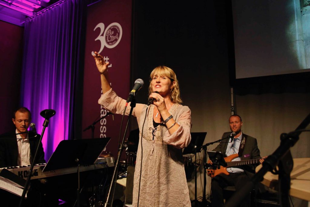 Kersti som solist sjunger och dirigerar på en scen i konsert på bokmässan